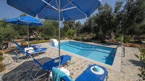 A swimming pool with lounge chairs and umbrellas, surrounded by greenery.