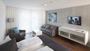 Una habitación de hotel moderna con cama, sofá, televisor y escritorio.