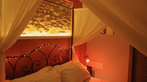 A bedroom with a bed under a canopy, a nightstand with a lamp, and a wall with a textured pattern. - Pekko Country House (Spello)