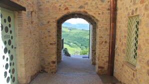 An arched stone doorway leading to a scenic view of a green valley. - Pekko Country House (Spello)