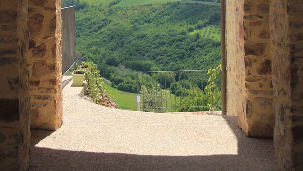 A stone archway leading to a balcony with a view of a green valley and mountains. - Pekko Country House (Spello)