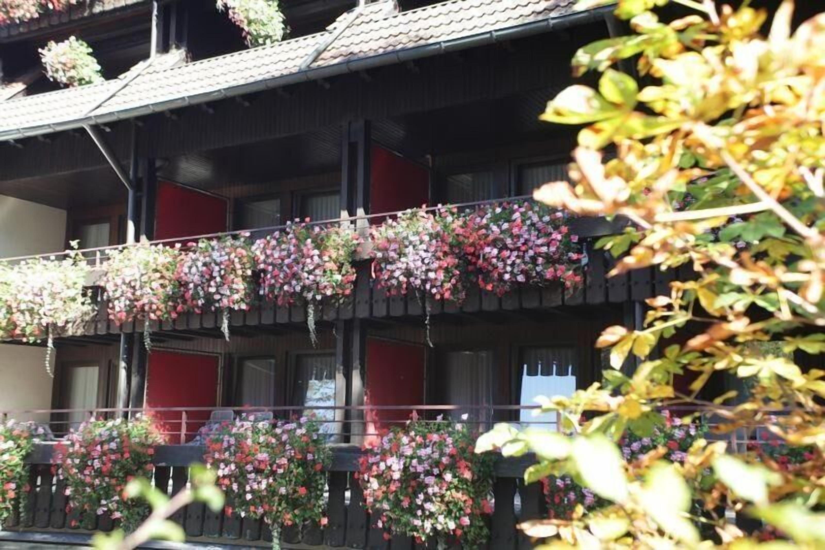 Un immeuble à plusieurs étages doté de balcons ornés de jardinières suspendues.