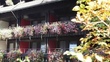 Un immeuble à plusieurs étages doté de balcons ornés de jardinières suspendues.