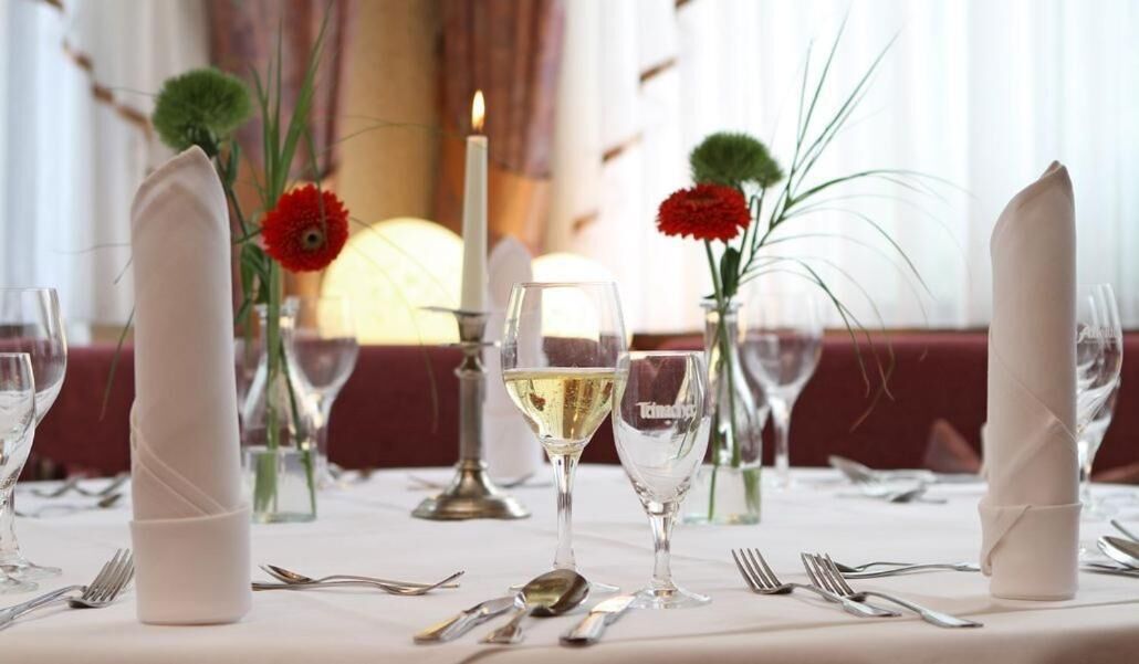 A table set for dining with wine glasses, cutlery, and a candle.