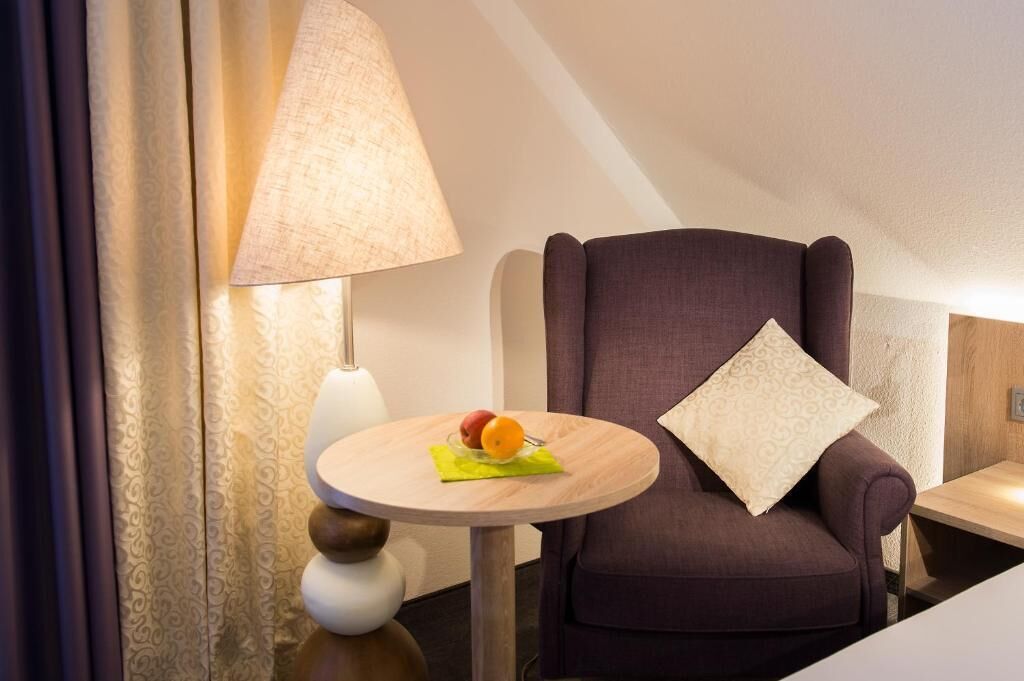 Et moderne værelse med en lilla lænestol, et rundt bord med en skål med frugt, og en lampe.
