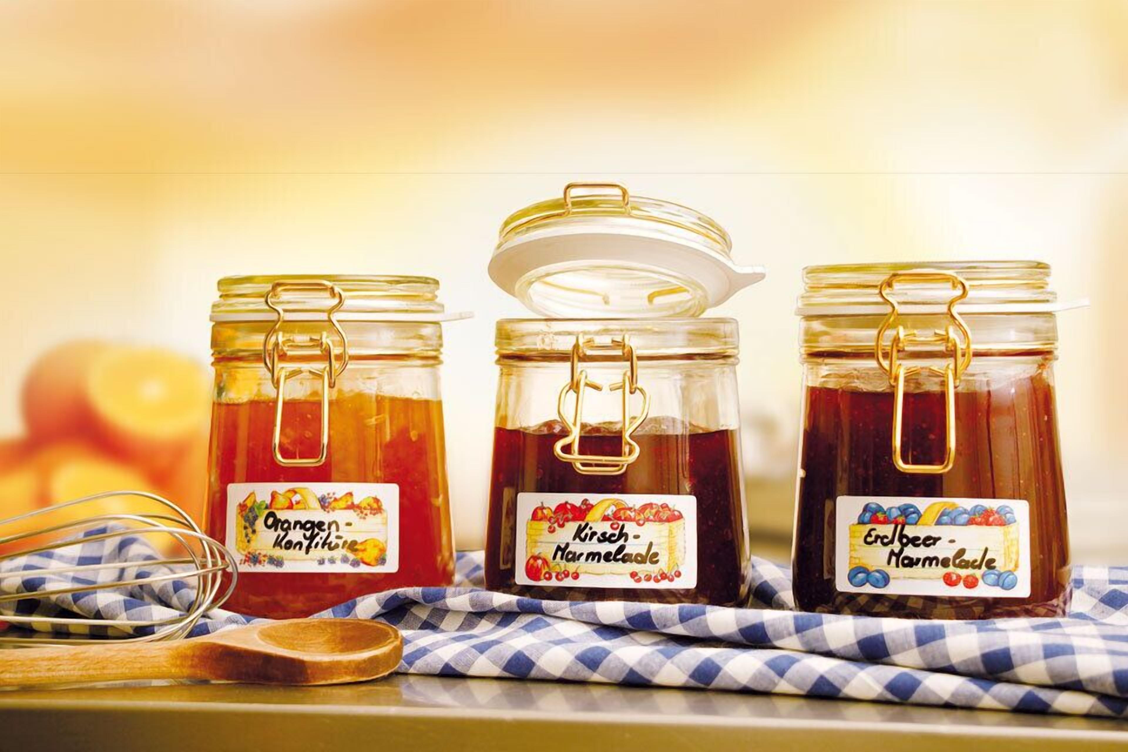 Three glass jars with metal clasps and labels, placed on a checkered cloth.