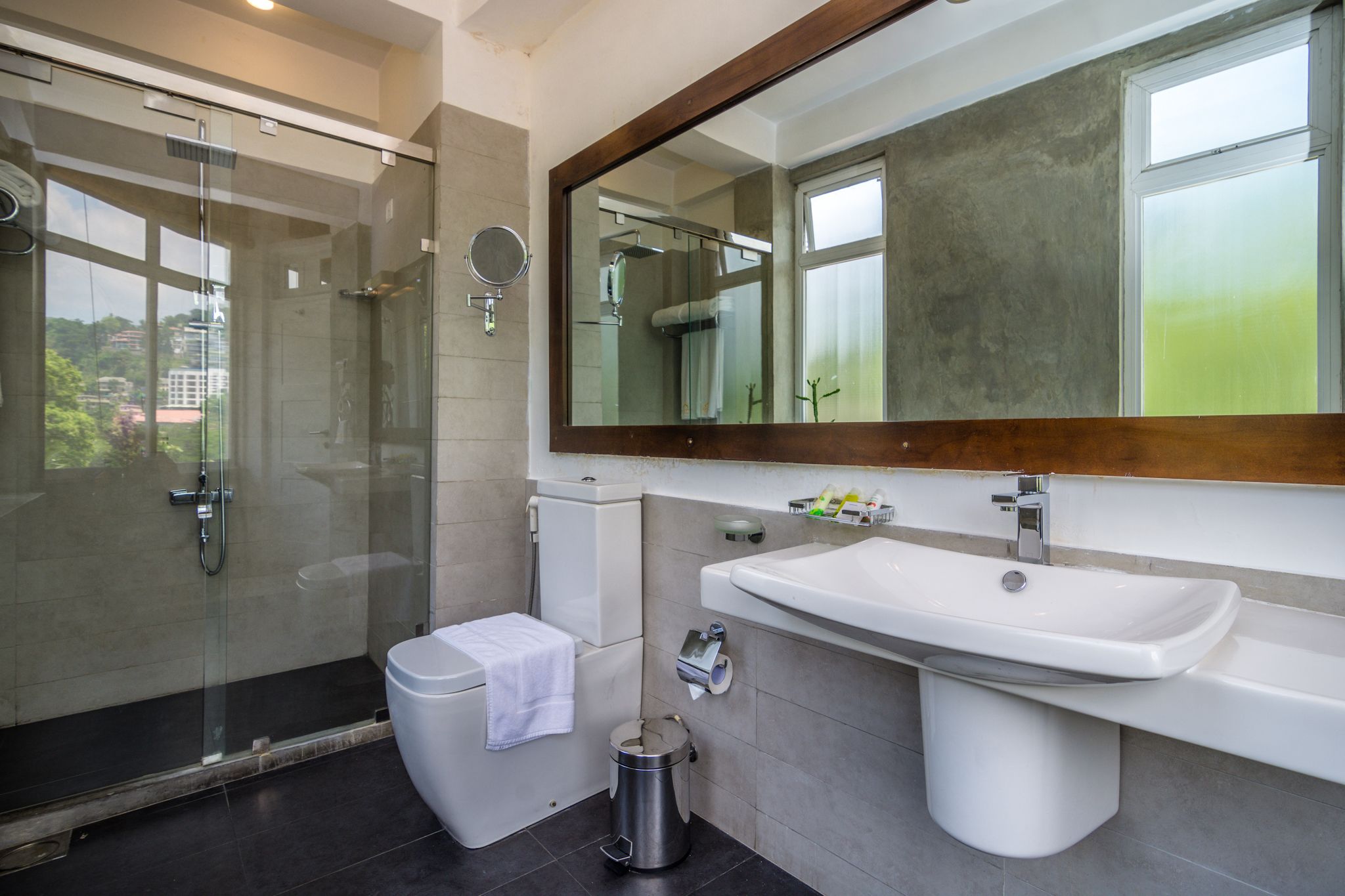 Een moderne badkamer met een douchecabine van glas, een toilet, een wastafel en een spiegel.