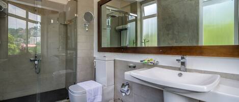 Een moderne badkamer met een douchecabine van glas, een toilet, een wastafel en een spiegel.