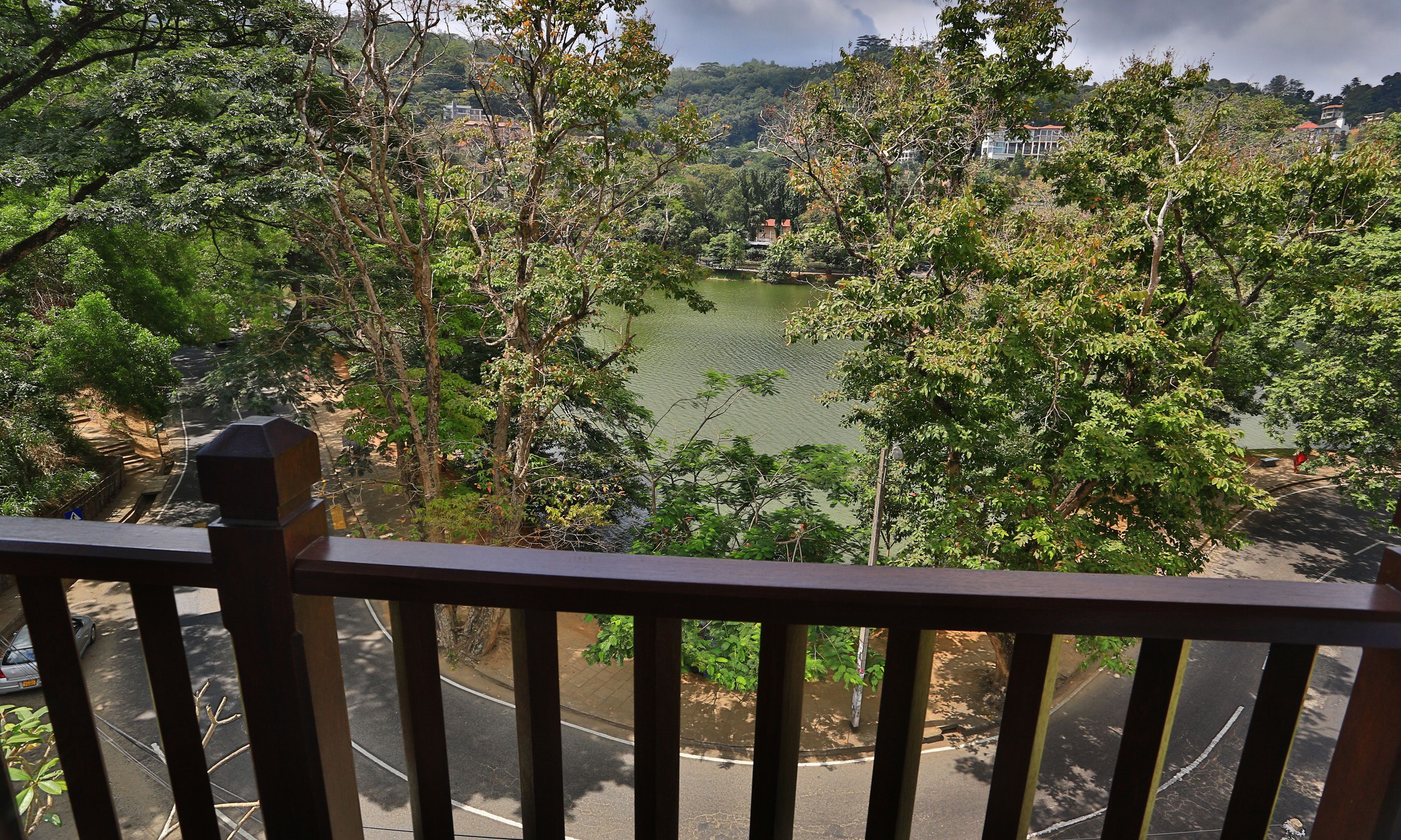 Vista desde un balcón con vista a un lago rodeado de árboles y edificios.