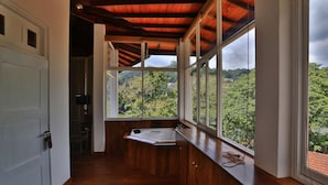 A bathroom with a wooden floor, a bathtub, and large windows offering a view of greenery and hills. - Viyana Boutique Hotel (Kandy)