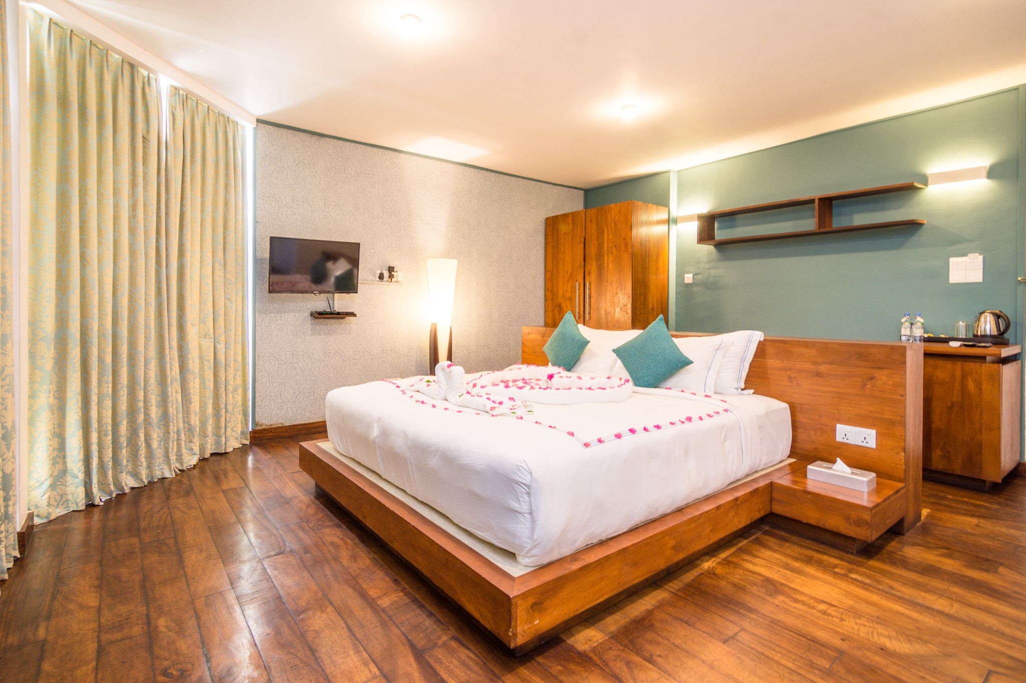 Habitación de hotel moderna con cama de madera, mesita de noche, armario de madera y televisor de pantalla plana.