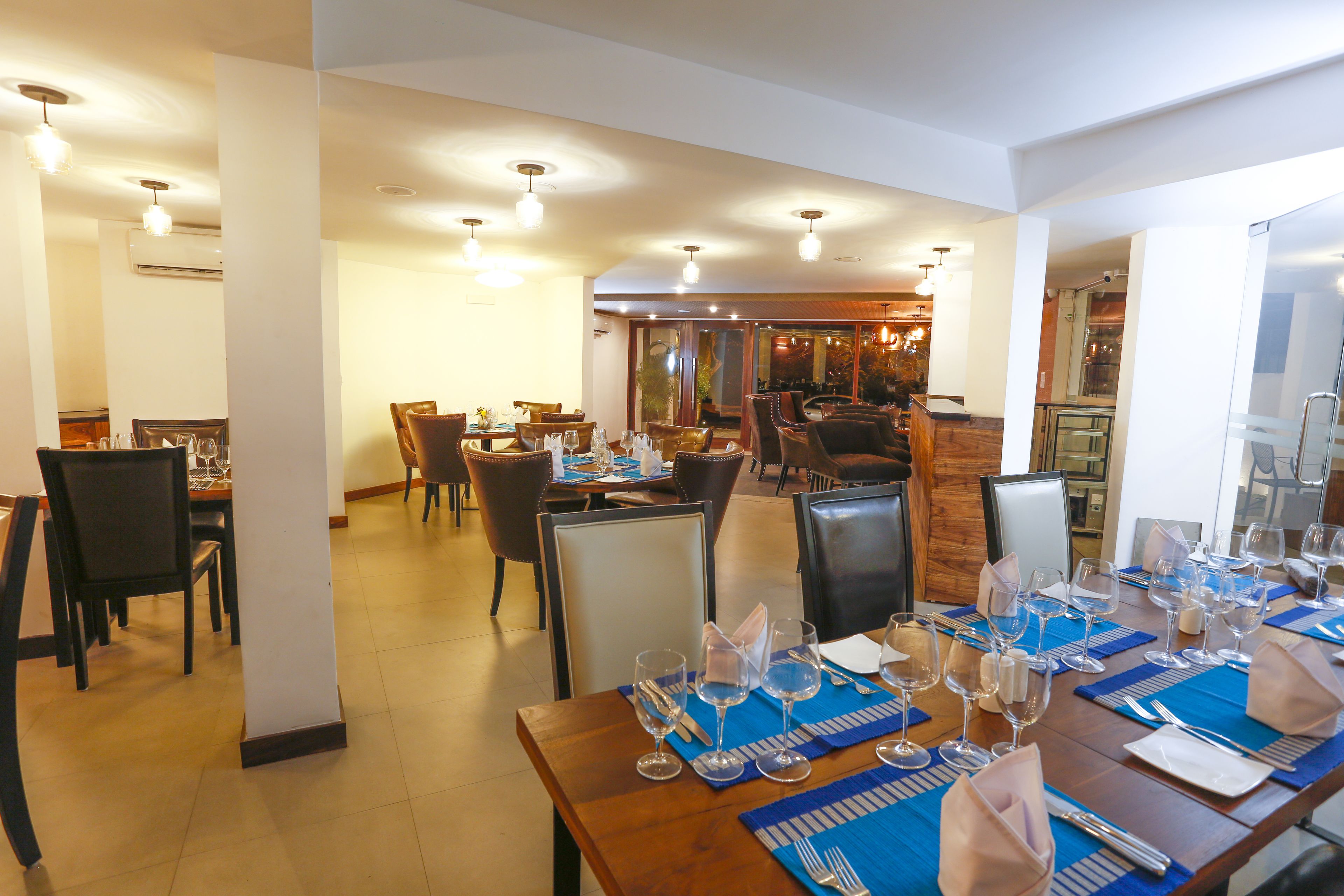 Comedor con varias mesas dispuestas para el servicio, sillas y una zona de bar al fondo.