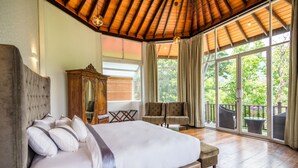 A spacious bedroom with a large bed, a wooden wardrobe, and a balcony with wicker furniture. - Viyana Boutique Hotel (Kandy)