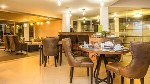 A modern dining area with leather chairs, a round table, and a bar counter. - Viyana Boutique Hotel (Kandy)