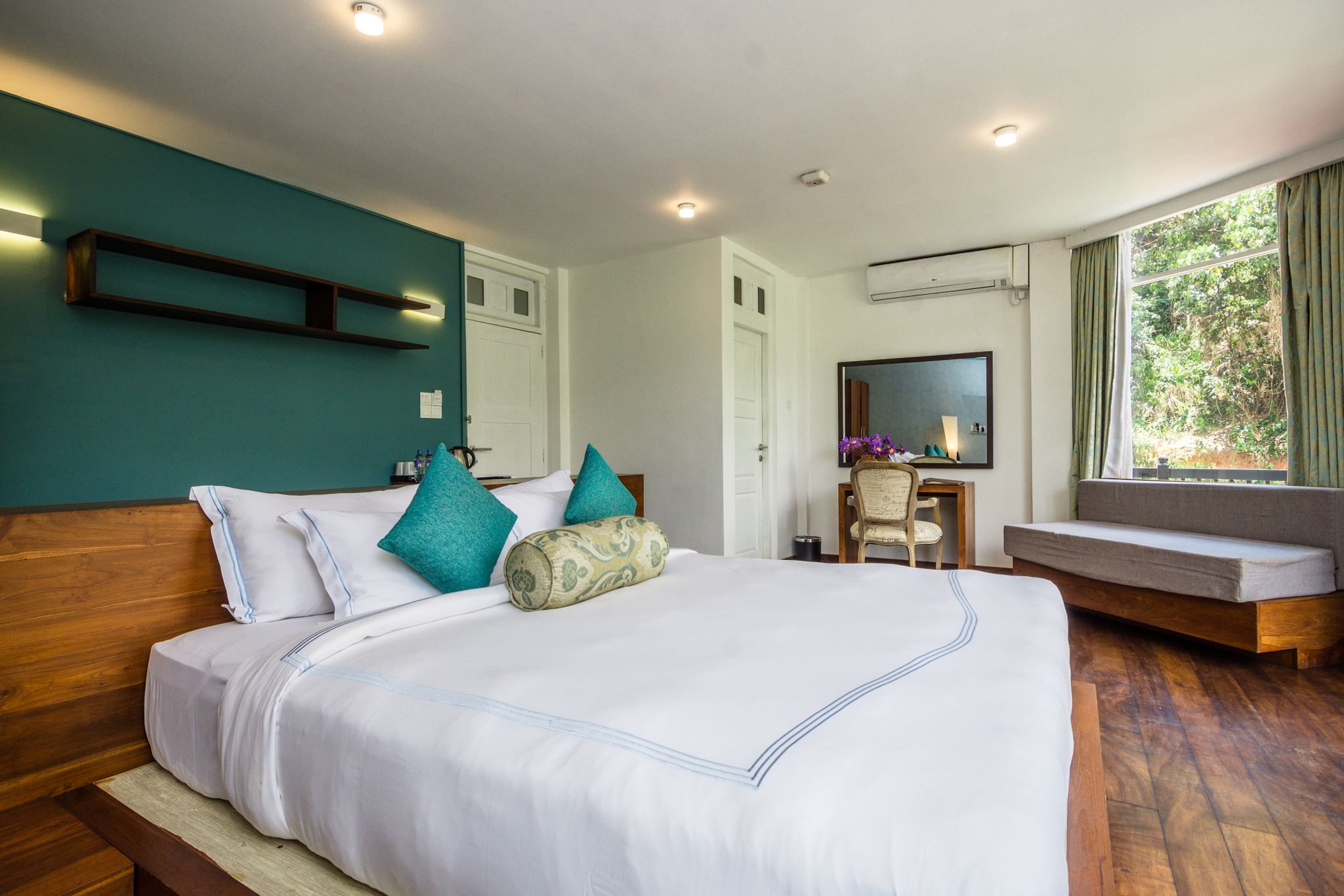 A hotel room with a large bed, a desk, and a window with curtains.