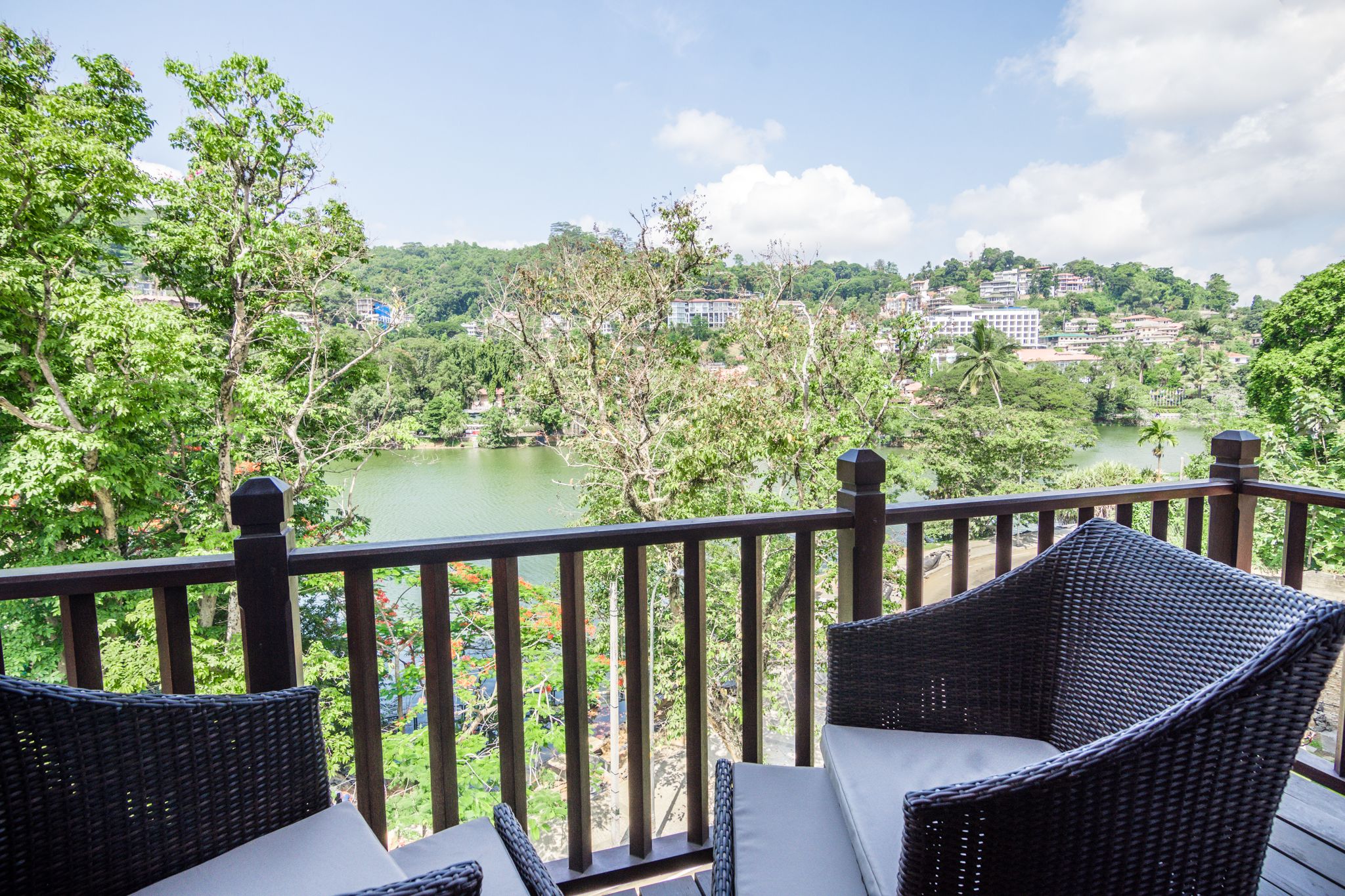 A balcony with wicker furniture overlooking a river and a cityscape.