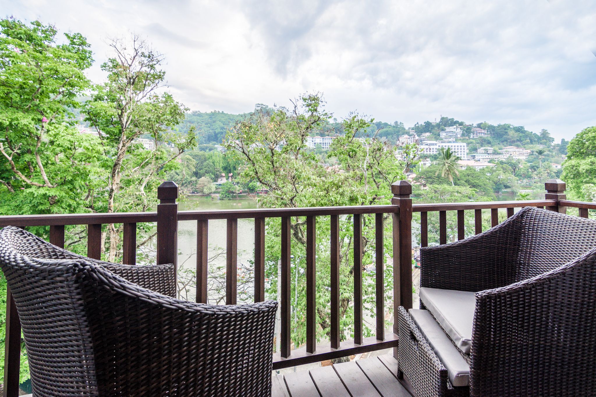 Een balkon met rieten meubels en uitzicht op een stadsgezicht.