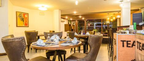 A restaurant with round tables, brown leather chairs, and a counter labeled "TEA".
