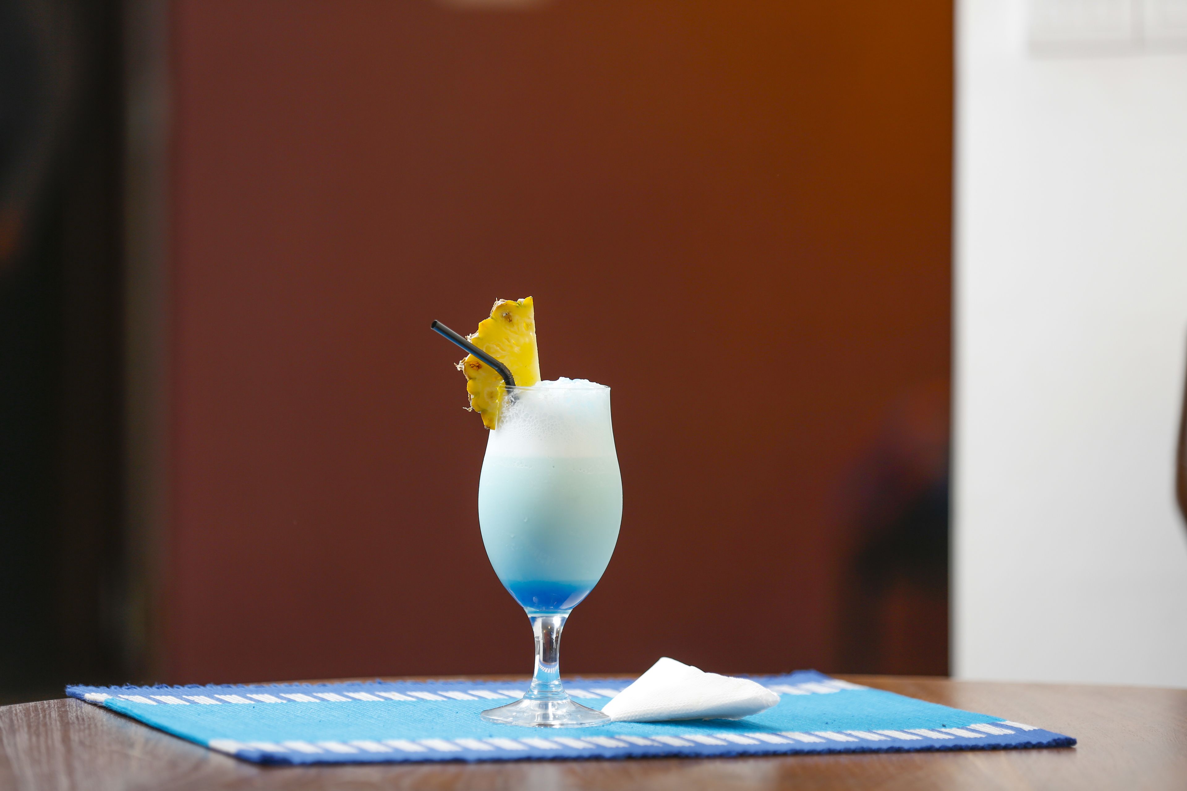 A cocktail in a glass on a blue placemat.