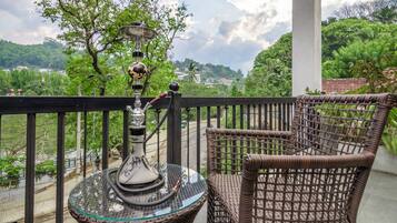 Varanda com móveis de vime, mesa de vidro e um cachimbo.