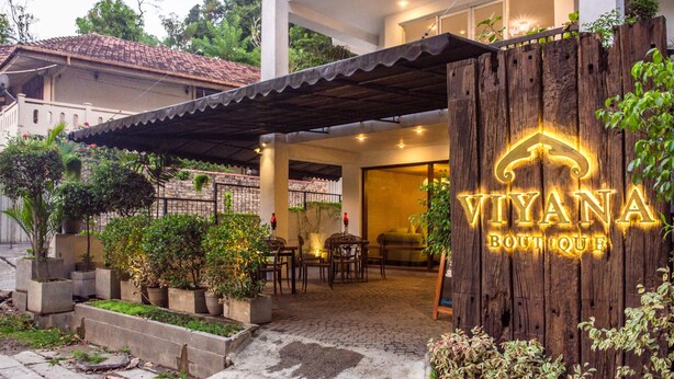 A boutique hotel entrance with a wooden sign, outdoor seating, and potted plants. - Viyana Boutique Hotel (Kandy)