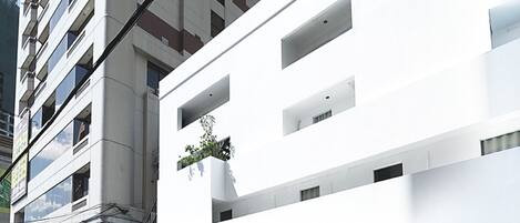 Un edificio moderno con fachada blanca, varios balcones y un escaparate visible con señalización.