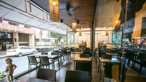 An indoor dining area with tables and chairs, large windows, and ceiling fans. - Hotel Durban (Makati)