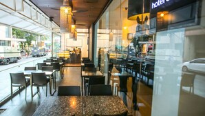 A modern hotel interior with a long dining area, glass walls, and a visible street view. - Hotel Durban (Makati)