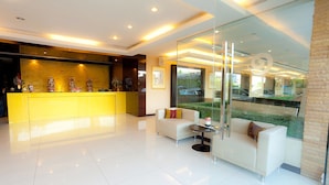 A modern reception area with a bright yellow desk, white sofas, and a glass partition. - The Residence Airport & Spa (Bangkok)