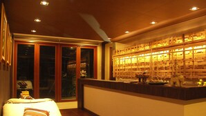A room with a bed, a massage table, and a wall with shelves containing various items. - The Residence Airport & Spa (Bangkok)