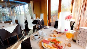 A breakfast setting with a table set for two, including plates with eggs, ham, and vegetables, a glass of orange juice, and a menu. - The Residence Airport & Spa (Bangkok)