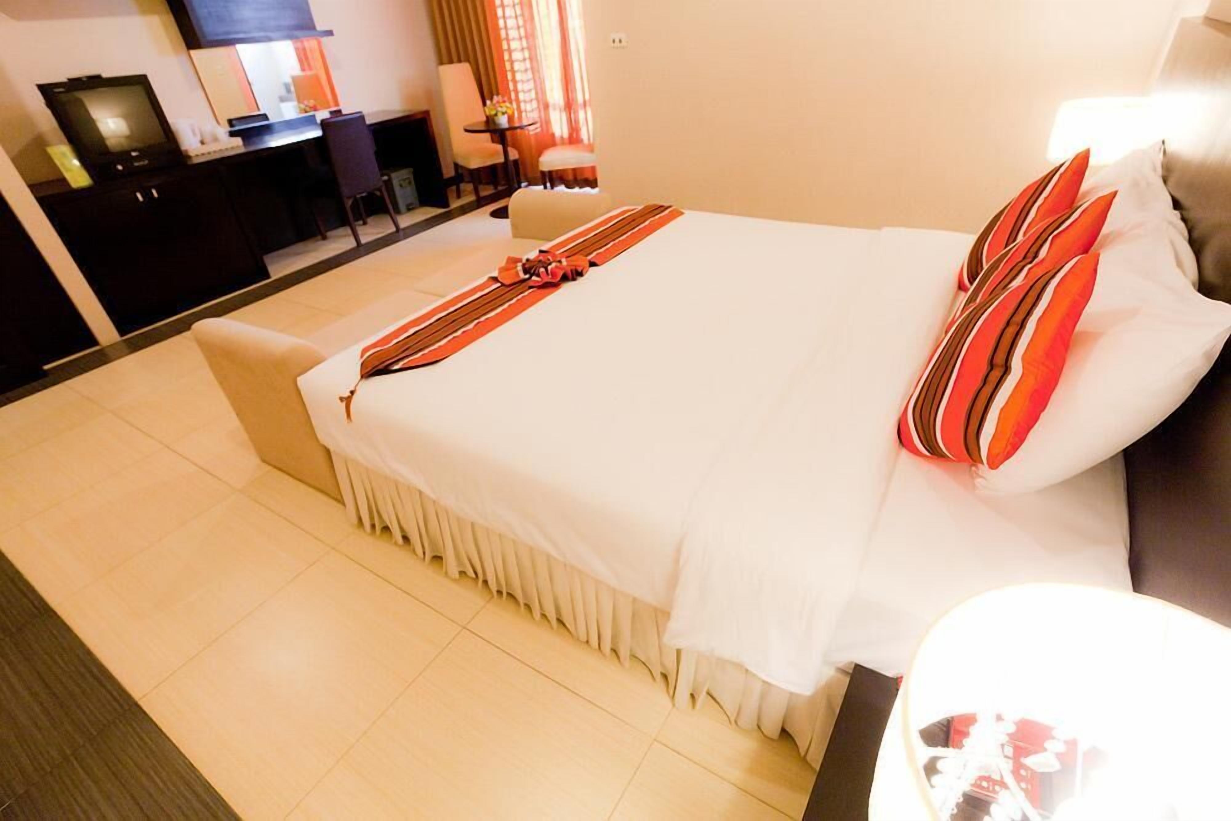 A hotel room with a large bed, a desk with a computer, and a television.