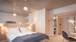 A modern hotel room with a large bed, bedside lamps, a desk with a chair, and a wardrobe. - Zander K Hotel (Bergen)