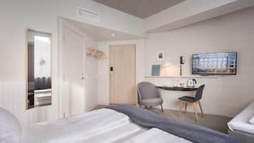 A hotel room with a bed, a desk with a chair, a television, and a wardrobe.