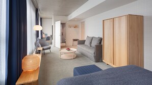 A modern hotel room with a large wardrobe, a sofa, a coffee table, and a desk with a lamp. - Zander K Hotel (Bergen)