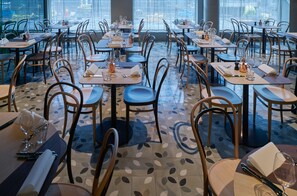 Ein Restaurant mit mehreren Tischen und Stühlen, ansprechend angeordnet in einem großzügigen Raum mit einem gemusterten Boden.
