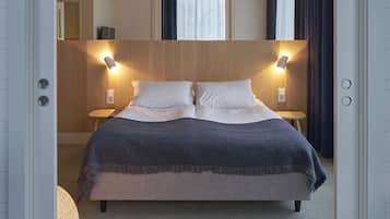 Una habitación de hotel moderna con una cama grande, dos lámparas de noche y vistas a la ciudad a través del ventanal.