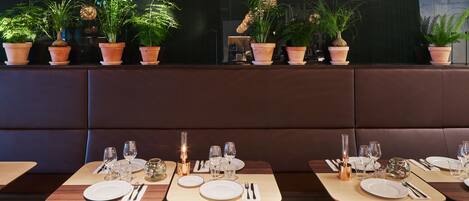 Un restaurante con cabinas y mesas, cada conjunto con platos, vasos y cubiertos.