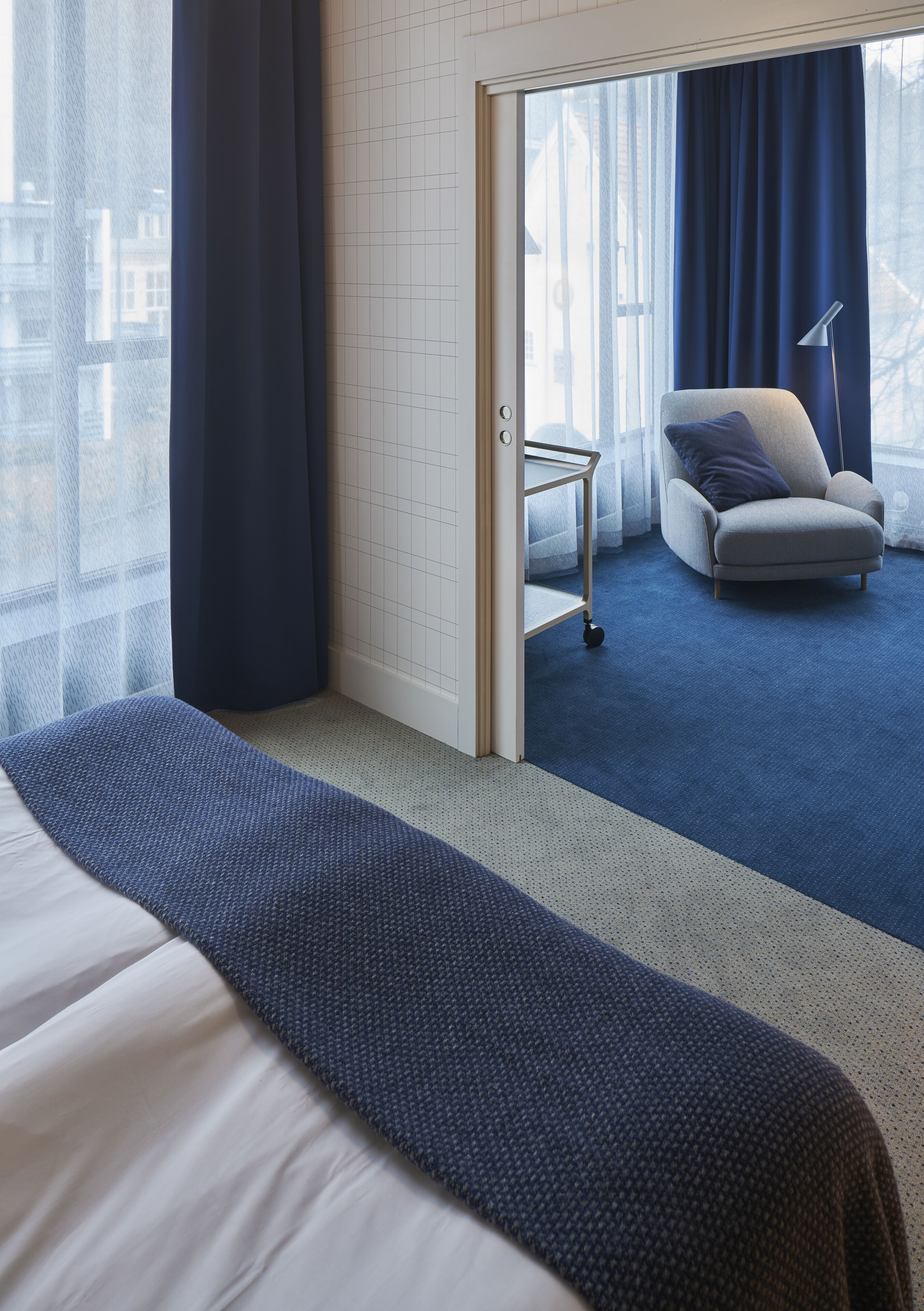 Una habitación de hotel con una cama, una silla, una mesita y vistas por una puerta.