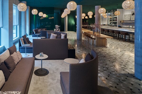 Ein stilvoller Lounge-Bereich mit Sofas, Sesseln, einer Bar und dekorativer Beleuchtung.