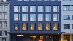 A modern hotel with a dark facade, multiple windows, and a visible entrance with a sign. - Zander K Hotel (Bergen)