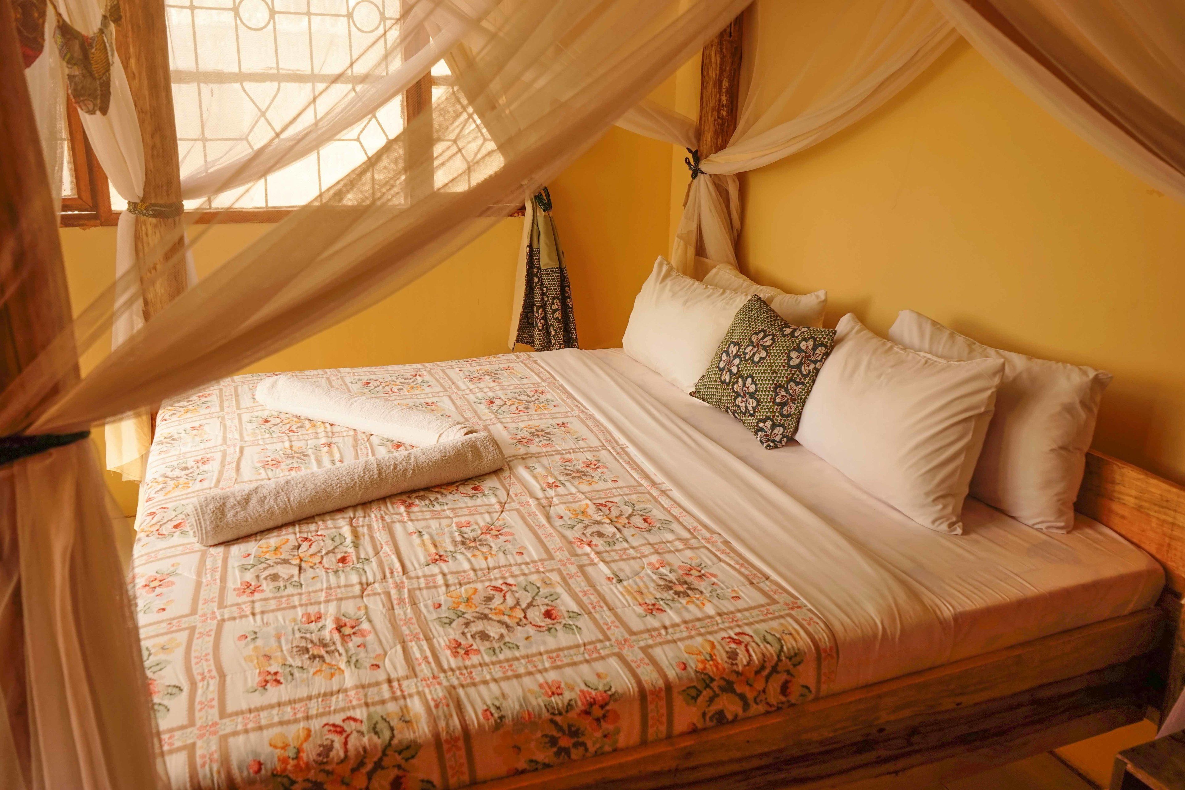 A bed with a floral bedspread, white pillows, and a canopy.