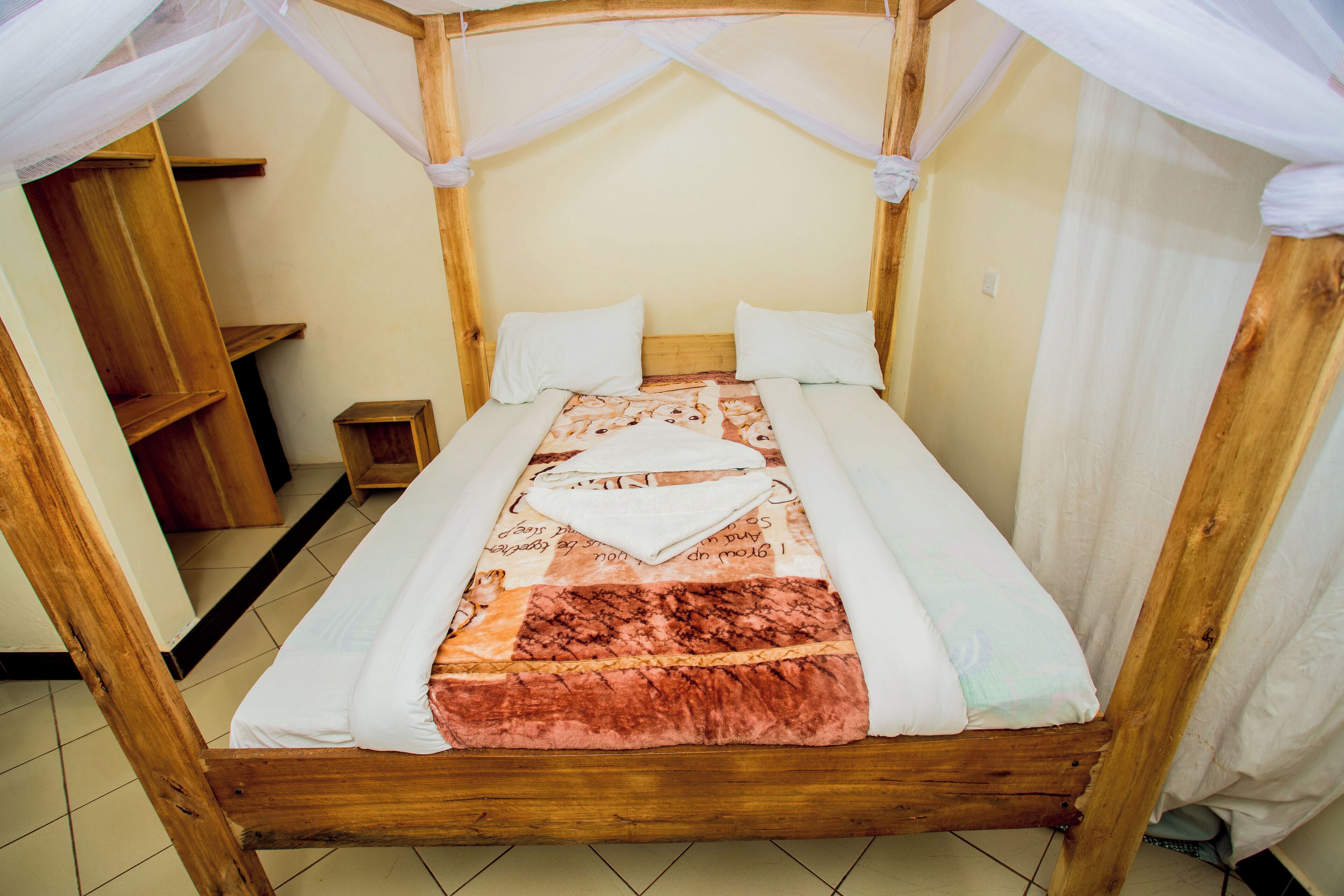 Una cama de madera con dosel, almohadas blancas y colcha.
