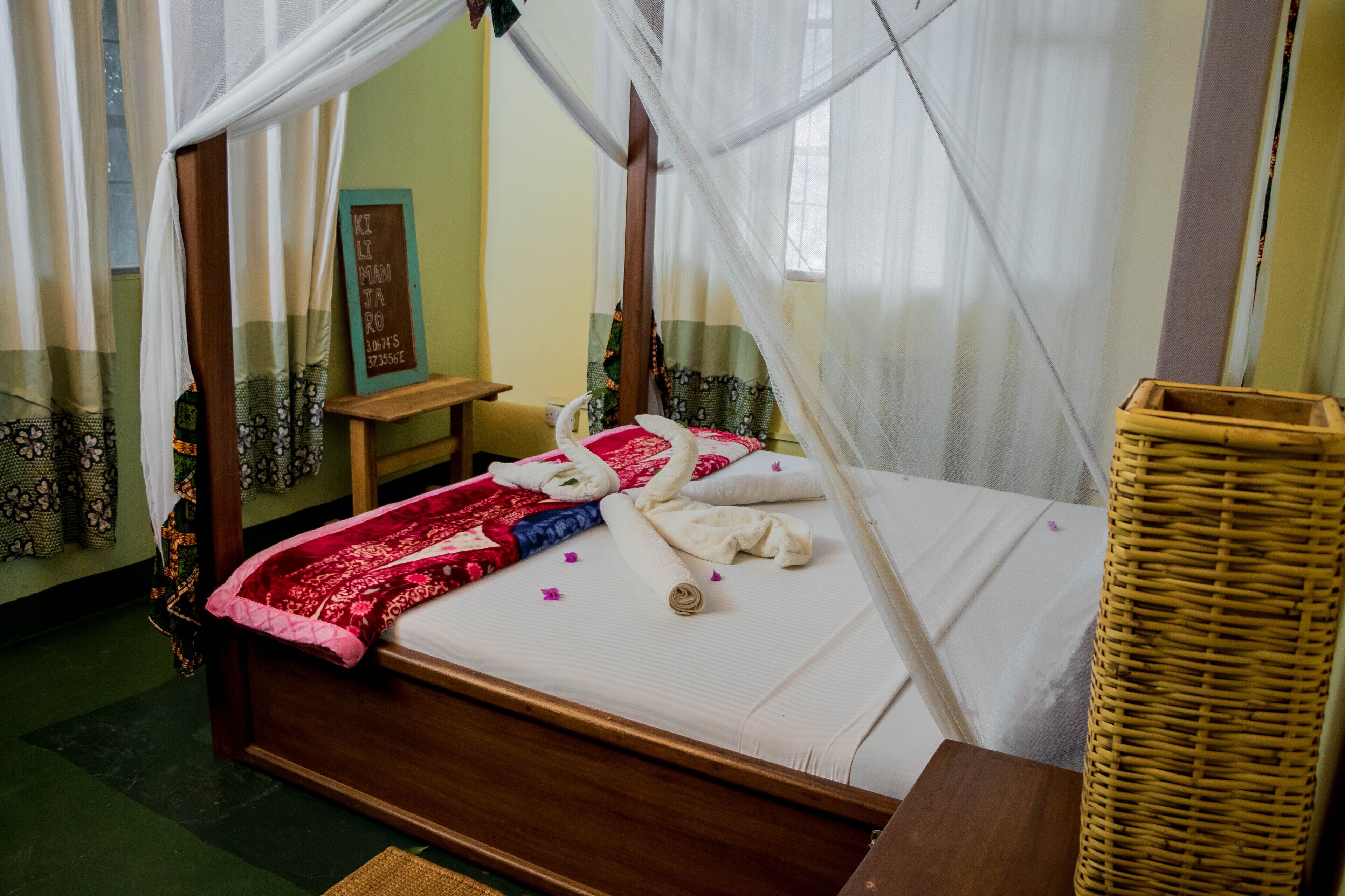 Una cama con dosel, una mesita de noche de madera, una cesta de mimbre y un letrero en la pared.