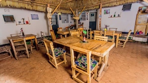 A rustic dining area with wooden tables and chairs, a thatched roof, and hexagonal tiled flooring. - The  Secret  Garden  Hotel  Moshi (Moshi)
