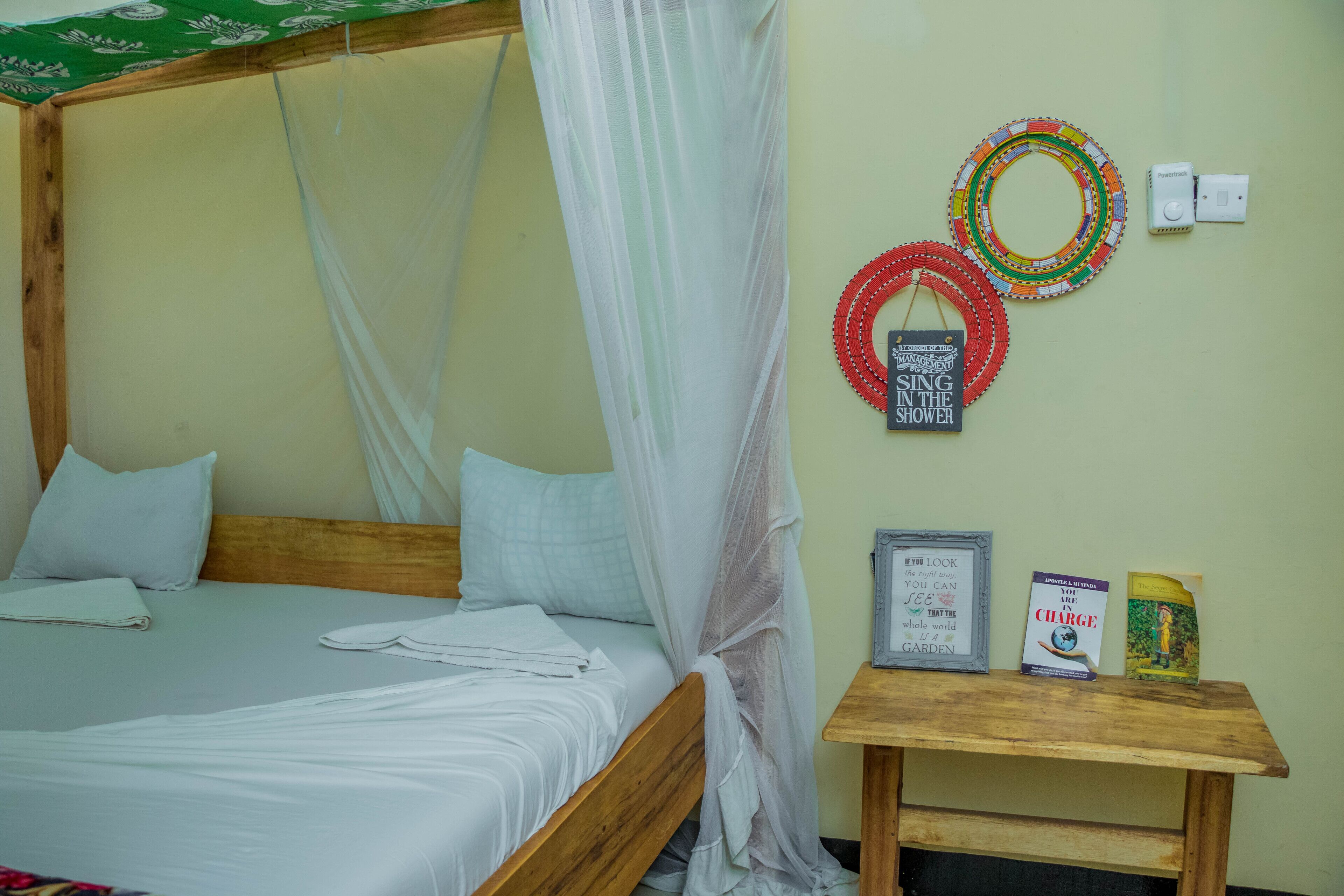 Una cama con dosel, una mesita de noche con libros y adornos en la pared.