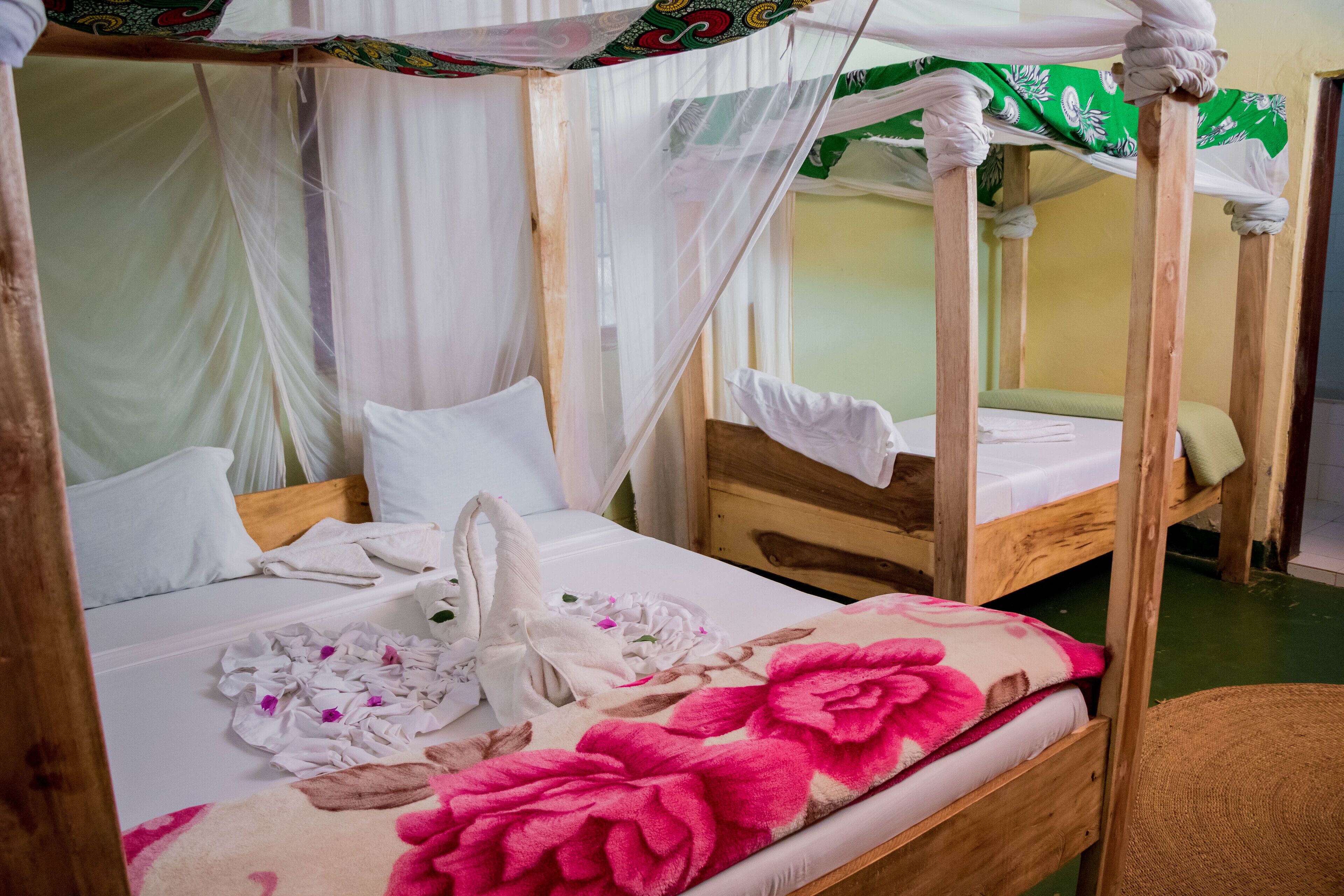 A room with two wooden beds, each with a canopy bedspread and white bedding.