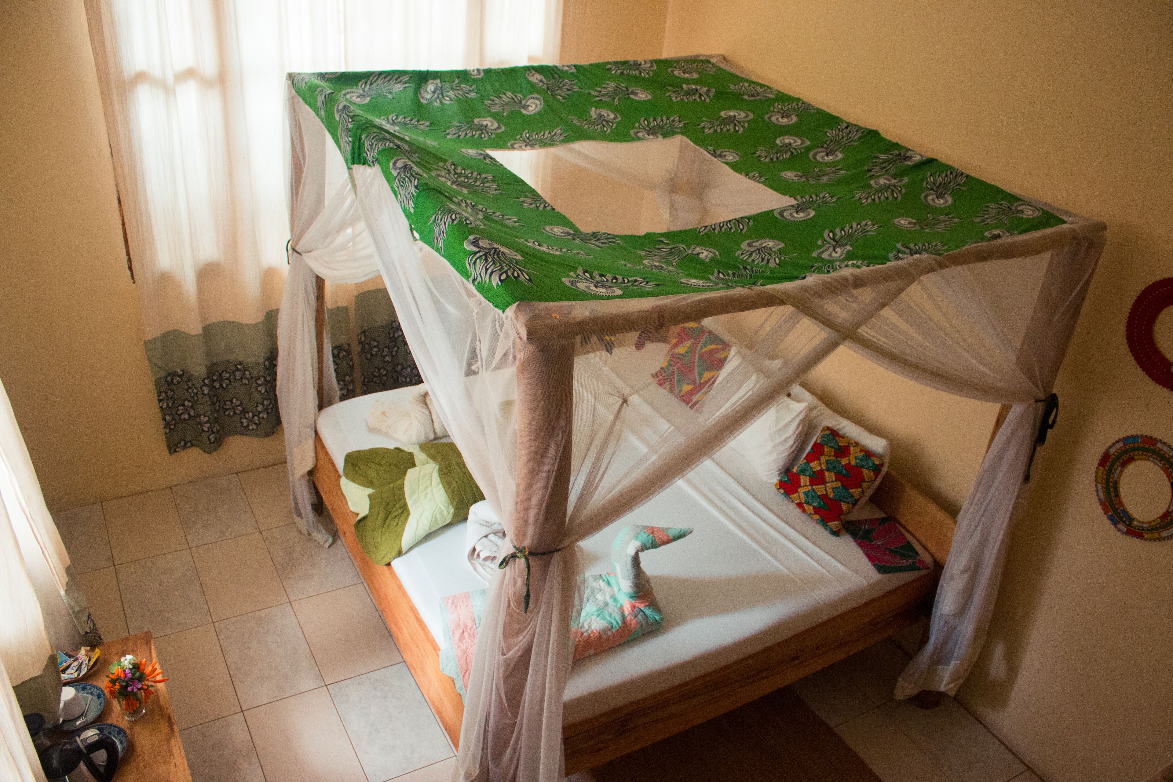 Un lit simple avec un baldaquin, une petite table avec un vase et un élément décoratif mural.