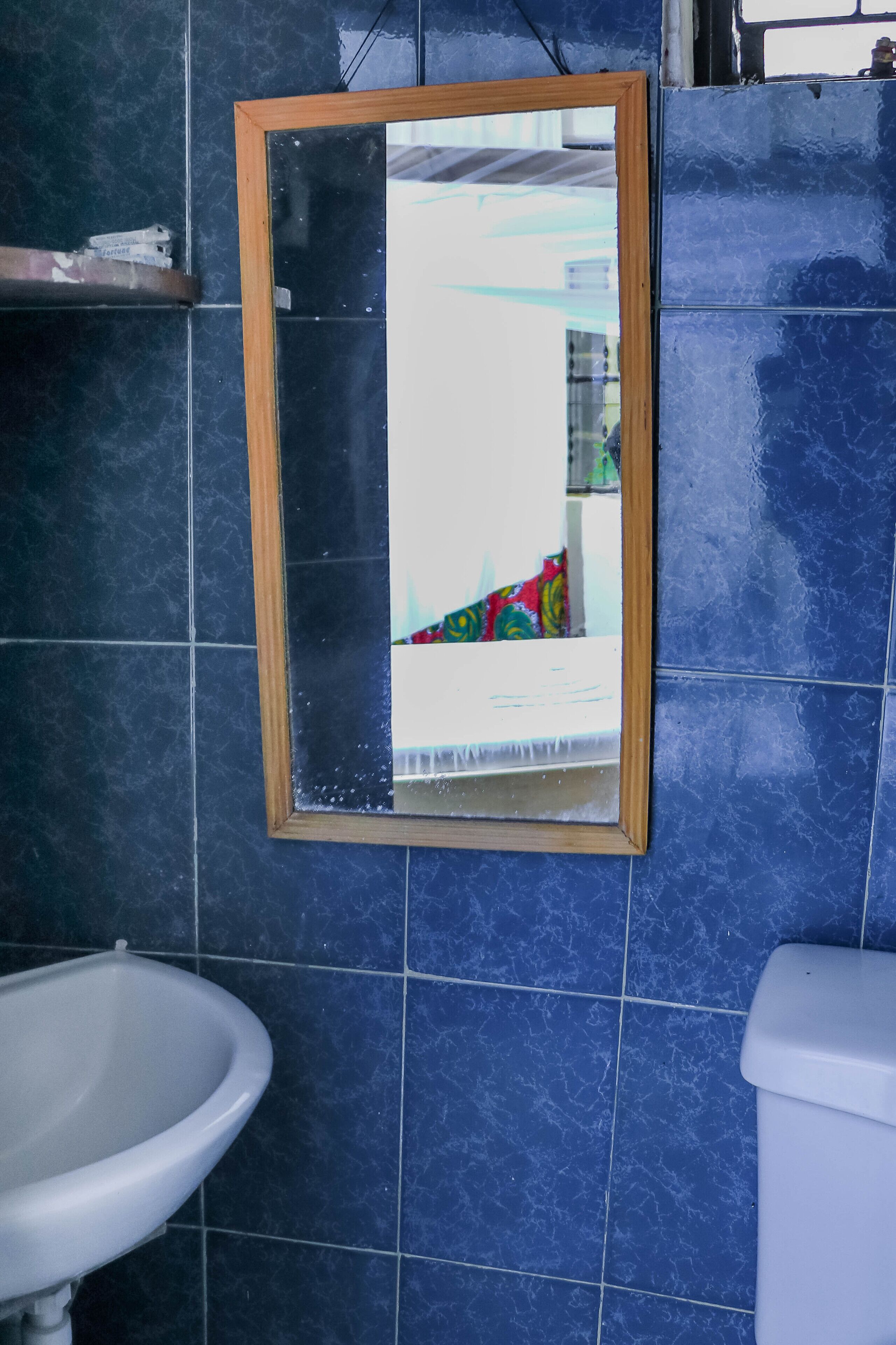 A bathroom with a mirror, sink, and toilet.