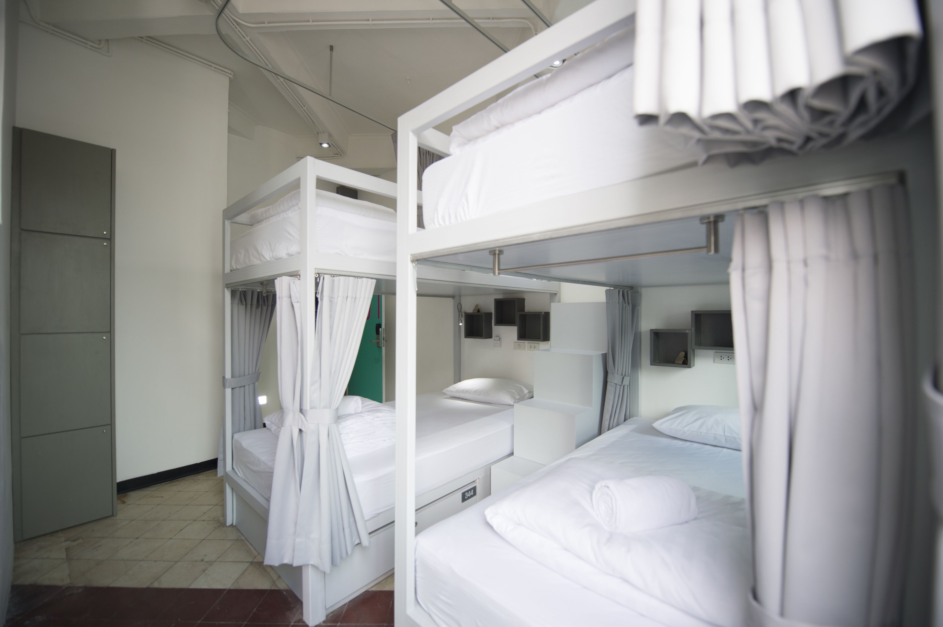 A dormitory room with bunk beds, a wardrobe, and a small desk.